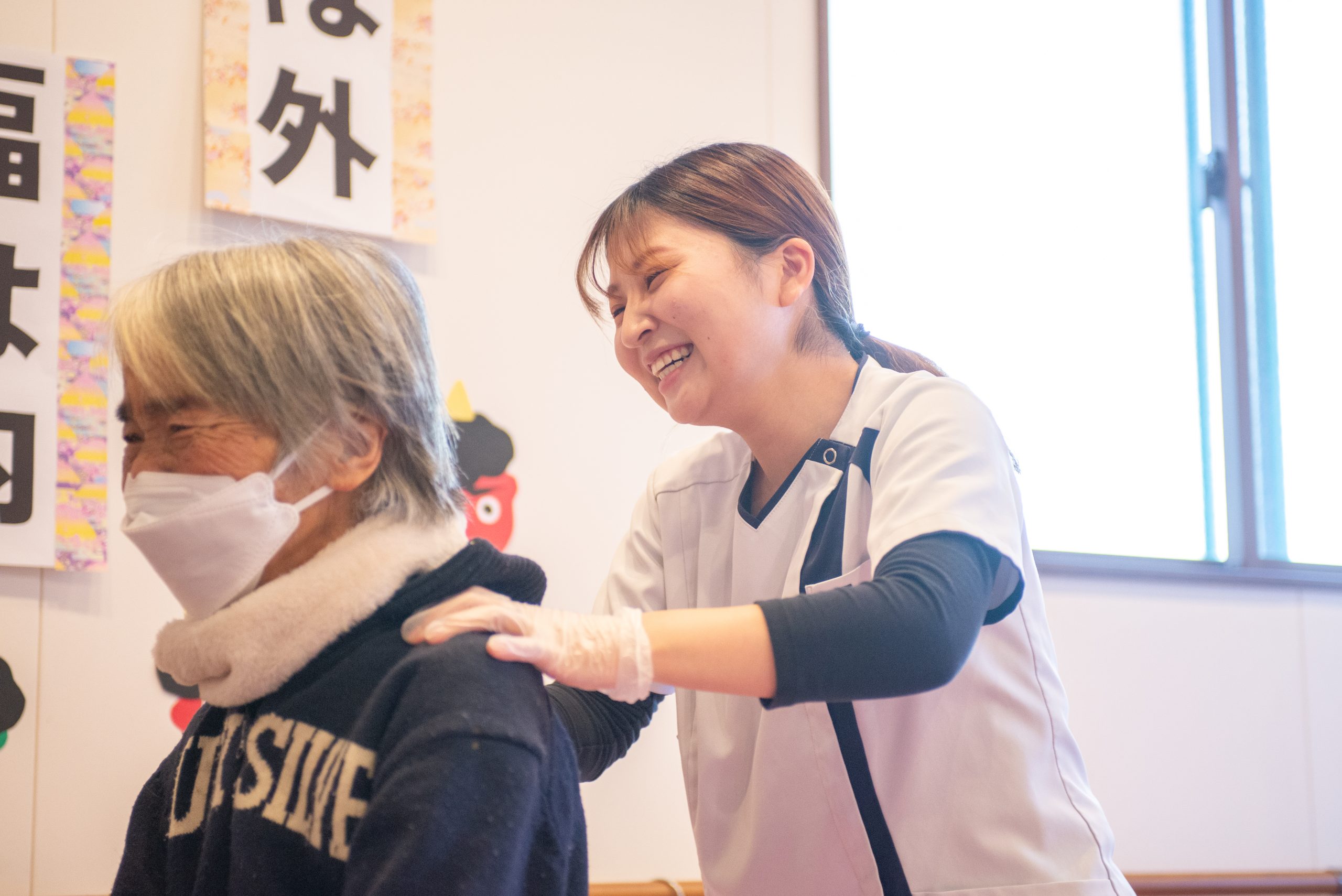 女性スタッフが利用者様の肩を笑顔でリハビリしている画像